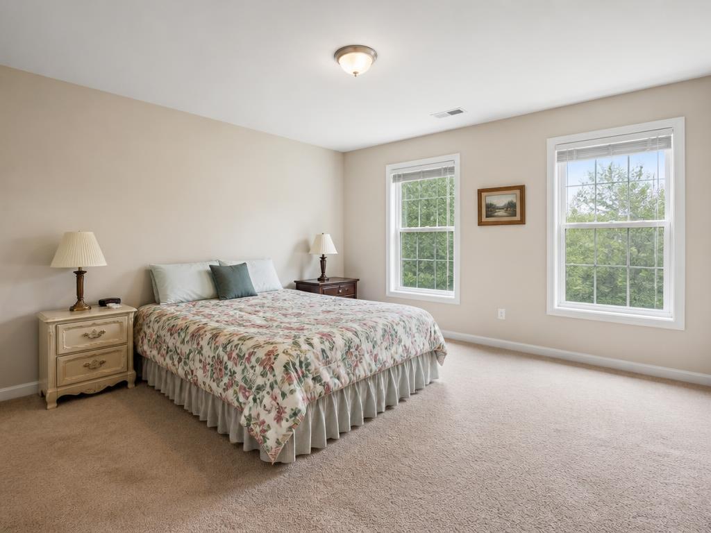 Spacious bedroom with plain walls and dated bedding