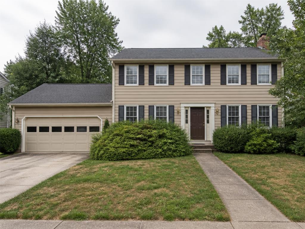 Two-story colonial home with dated paint and overgrown shrubs before a refresh